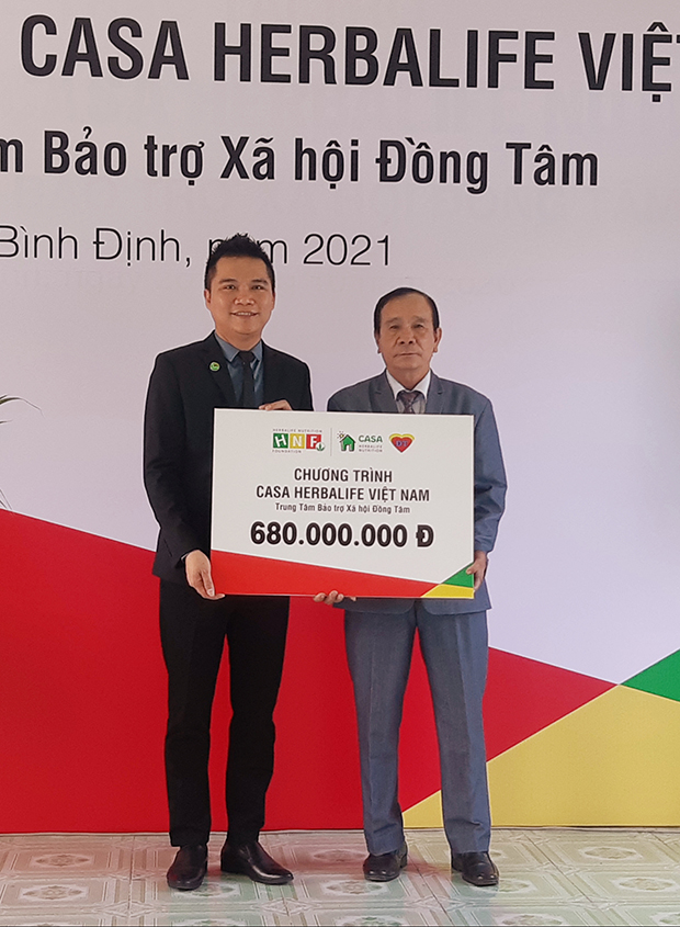 Đại diện Herbalife Việt Nam (bên trái) trao bảng tượng trưng số tiền tài trợ cho lãnh đạo Trung tâm Đồng Tâm