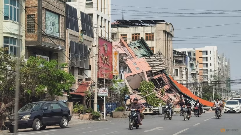 Người dân đi xe máy qua một tòa nhà bị đổ sập sau trận động đất ở Mandalay, Myanmar hôm 28/3. Ảnh: Reuters.